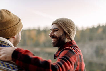 Seitenansicht eines glücklichen Mannes mit Bart, der einen männlichen Freund ansieht - MASF34245