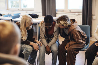 Female friends consoling sad teenage girl in group therapy - MASF34272