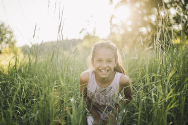 Portrait of happy girl playing in grass during sunny day - MASF34401