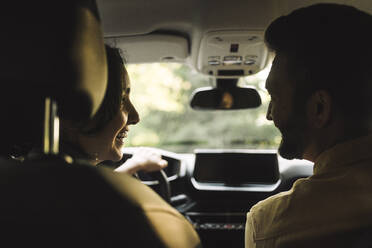 Happy woman looking at man sitting in car - MASF34405