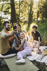 Vater macht beim Picknick ein Selfie mit seiner Familie über sein Smartphone - MASF34408