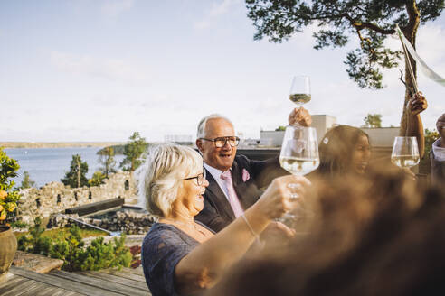 Glückliche Freunde stoßen mit Weingläsern während einer Hochzeitsfeier an - MASF34428