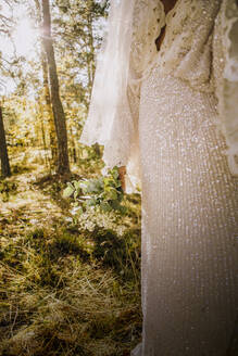 Midsection von Mitte Erwachsenen Braut trägt weißes Hochzeitskleid im Wald - MASF34451