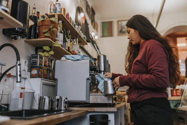 Seitenansicht einer Unternehmerin beim Kaffeekochen in einem Café - MASF34474