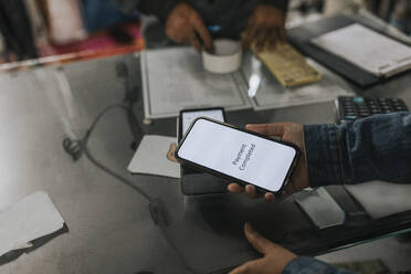 Hand of woman making contactless payment through smart phone in workshop - MASF34524