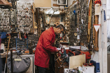 Side view of male locksmith working in repair shop - MASF34533