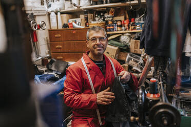 Portrait of smiling locksmith with leather working in repair shop - MASF34537