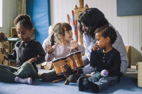 Lehrerin bringt Mädchen in einer Kindertagesstätte das Schlagzeugspielen bei - MASF34556