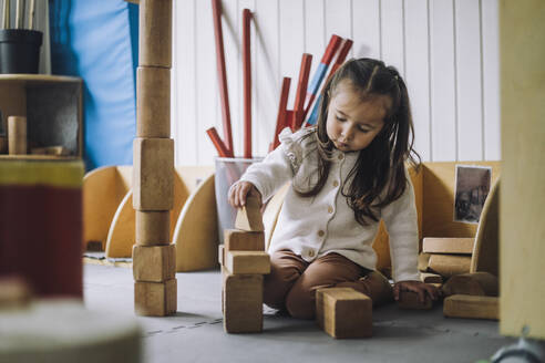 Mädchen stapelt Spielzeugblöcke, während sie im Kindergarten sitzt - MASF34557