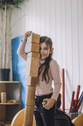 Lächelndes Mädchen stapelt Holzklötze im Kindergarten - MASF34560