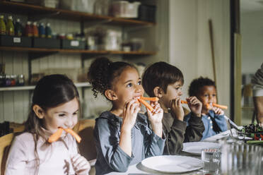 Gemischtrassige Kinder essen Karotten zum Frühstück in der Kindertagesstätte - MASF34570