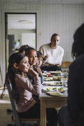 Smiling girl talking with teacher by classmates having breakfast in kindergarten - MASF34583