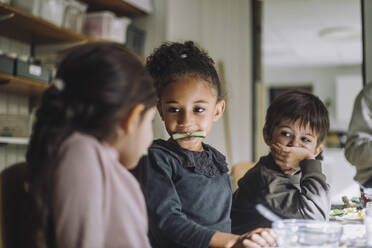 Multirassische Schülerinnen essen Gurke von männlichen Klassenkameraden in der Kindertagesstätte - MASF34586