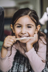 Porträt eines lächelnden Mädchens, das in einer Kindertagesstätte Eis isst - MASF34600