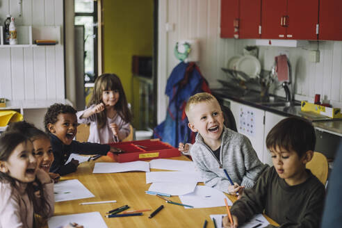 Cheerful male and female students enjoying while learning in kindergarten - MASF34620