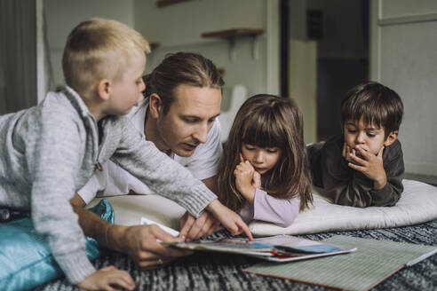 Männlicher Kinderbetreuer liest Kindern im Kindergarten ein Buch vor - MASF34626