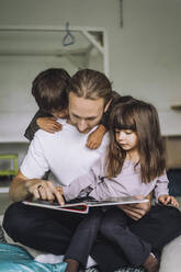 Männlicher Lehrer liest Kindern in der Kindertagesstätte eine Geschichte vor - MASF34628