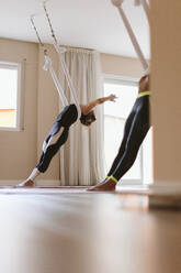 Frauen mit erhobenen Armen im Aerial-Yoga-Kurs - OCAF00794