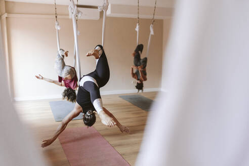 Frauen bei Dehnungsübungen in einer Aerial-Yoga-Klasse - OCAF00804