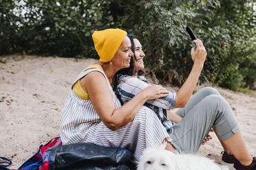 Glückliche Frauen nehmen Selfie durch Smartphone im Park - MRRF02575