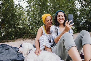 Glückliche Frauen nehmen Selfie durch Handy im Park - MRRF02576