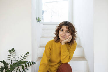 Lächelnde junge Frau auf einer Treppe zu Hause sitzend - VRAF00048