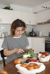 Junge Frau schneidet Gemüse in der Küche zu Hause - VRAF00054