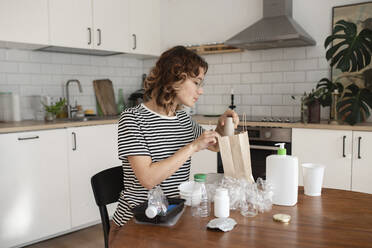 Frau recycelt Plastikmüll in der Küche zu Hause - VRAF00057