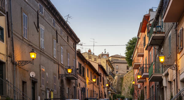 Italien, Latium, Capodimonte, Häuserzeilen und leuchtende Straßenlaternen in der Abenddämmerung - MAMF02466