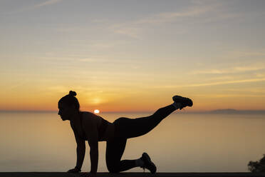 Silhouette Frau übt Yoga bei Sonnenuntergang - LJF02459
