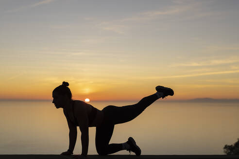 Silhouette woman practicing yoga at sunset - LJF02459
