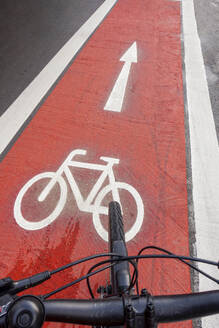 Germany, Bavaria, Munich, Bicycle moving along red bicycle lane - MAMF02487