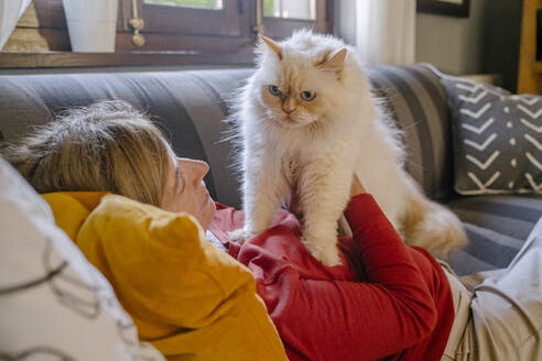 Frau mit Katze auf Sofa liegend zu Hause - MMPF00585