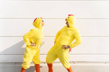 Freunde in Hühnerkostümen haben Spaß vor einer Wand - OIPF02869