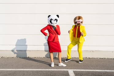 Man and woman wearing animal mask standing in front of wall - OIPF02909