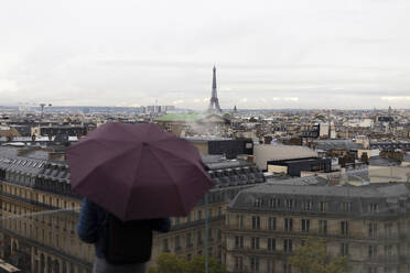 Frankreich, Ile-de-France, Paris, Stadtsilhouette mit stehendem Mann mit Regenschirm im Vordergrund - MMPF00648