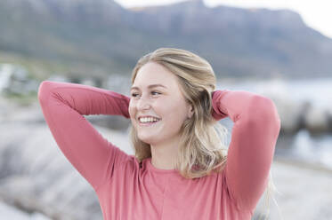 Cheerful young woman standing with hands behind head - MEF00163