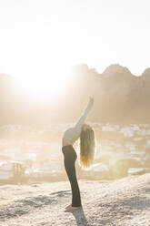 Woman doing stretching exercise on rock at sunrise - MEF00174