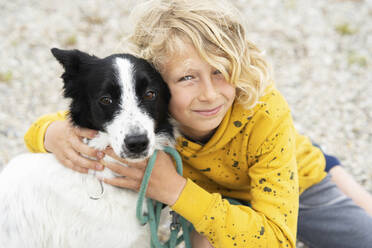 Happy blond boy embracing Border Collie dog - NJAF00200