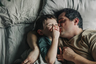 Father kissing cute son in bed - VSNF00375