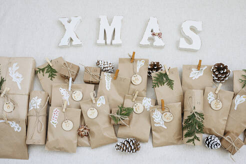 Papiertüten mit Tannenzapfen und Weihnachtsschmuck auf dem Teppich - SSYF00036