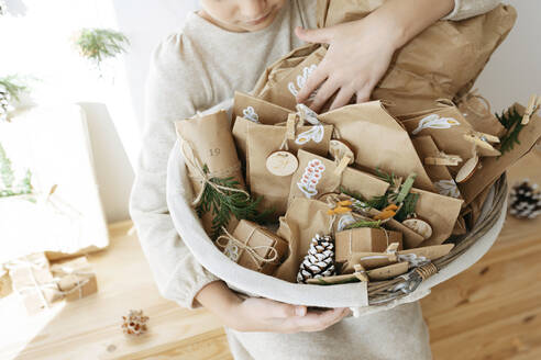 Girl holding basket of advent calendar gifts at home - SSYF00048