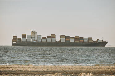 Netherlands, Zeeland, Groede, Container ship with beach in foreground - FDF00343