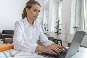 Reife Geschäftsfrau mit Laptop auf dem Schreibtisch im Büro - VPIF07793