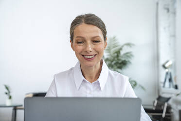 Happy mature businesswoman using laptop at office - VPIF07794