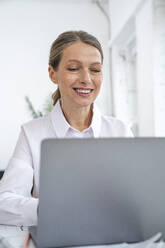 Glückliche Geschäftsfrau mit Laptop im Büro - VPIF07795