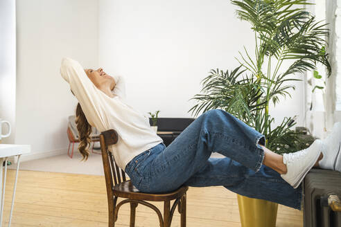Glückliche Geschäftsfrau entspannt sich auf einem Stuhl im Büro - VPIF07859