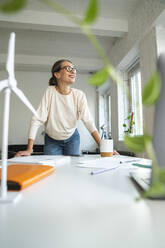 Smiling mature businesswoman standing at table in office - VPIF07868