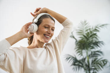 Glückliche Geschäftsfrau mit drahtlosen Kopfhörern tanzt im Büro - VPIF07872
