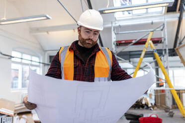 Young engineer examining blueprint at construction site - WPEF06938